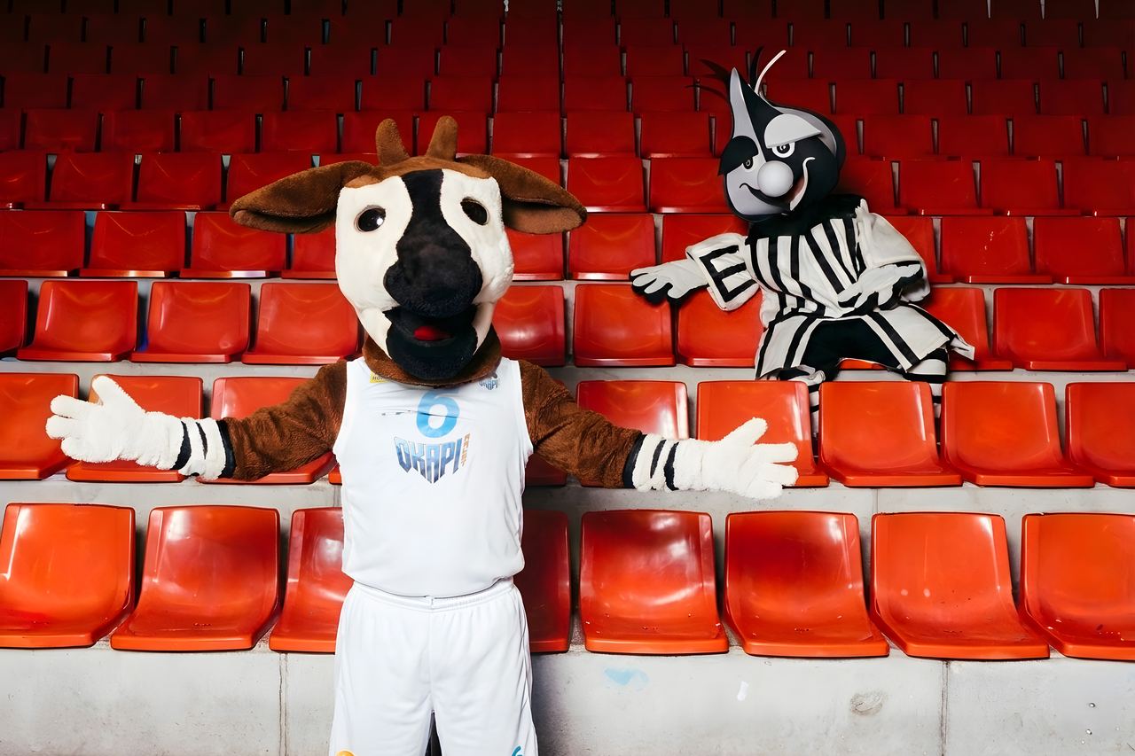 De okapi van Okapi Aalst poseert in de tribune, de mascotte van Eendracht zit erachter.